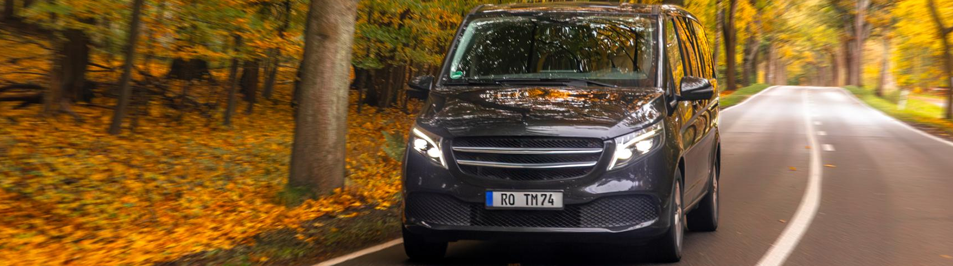Luxury van driving through an autumn forest